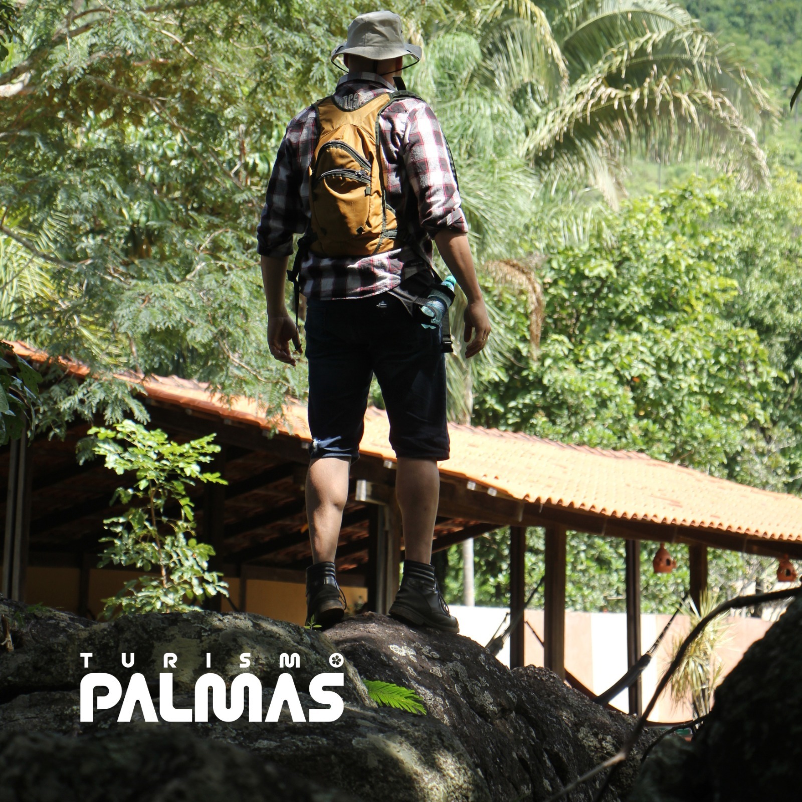 Imagem de um homem em cima de uma rocha com uma mochila e um chapeu